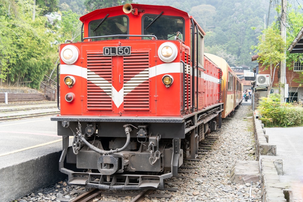 a red train traveling down train tracks next to a forest