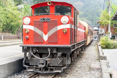 a red train traveling down train tracks next to a forest