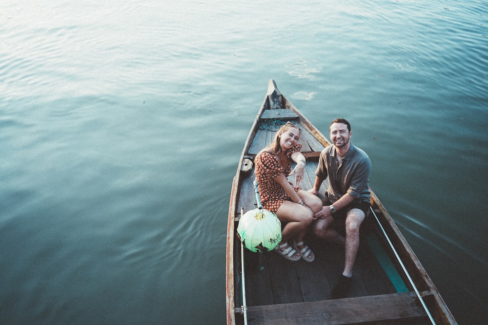 a man and a woman sitting on a boat in the water