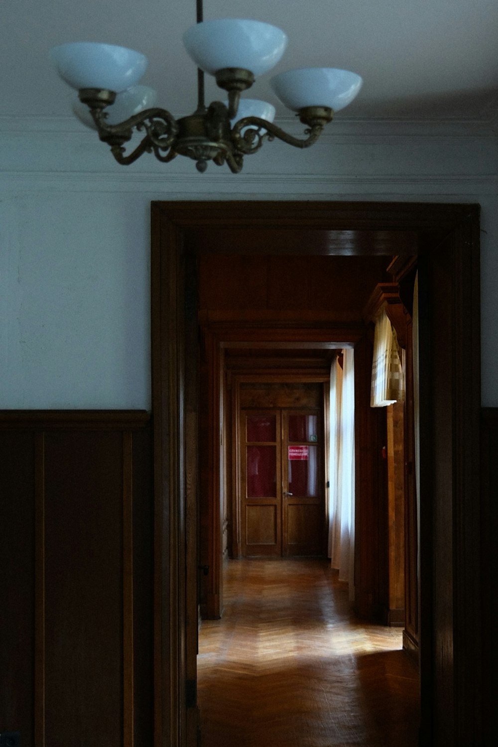un pasillo con una lámpara de araña y suelos de madera
