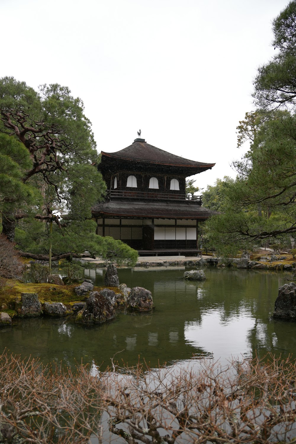 a pagoda in the middle of a pond surrounded by trees