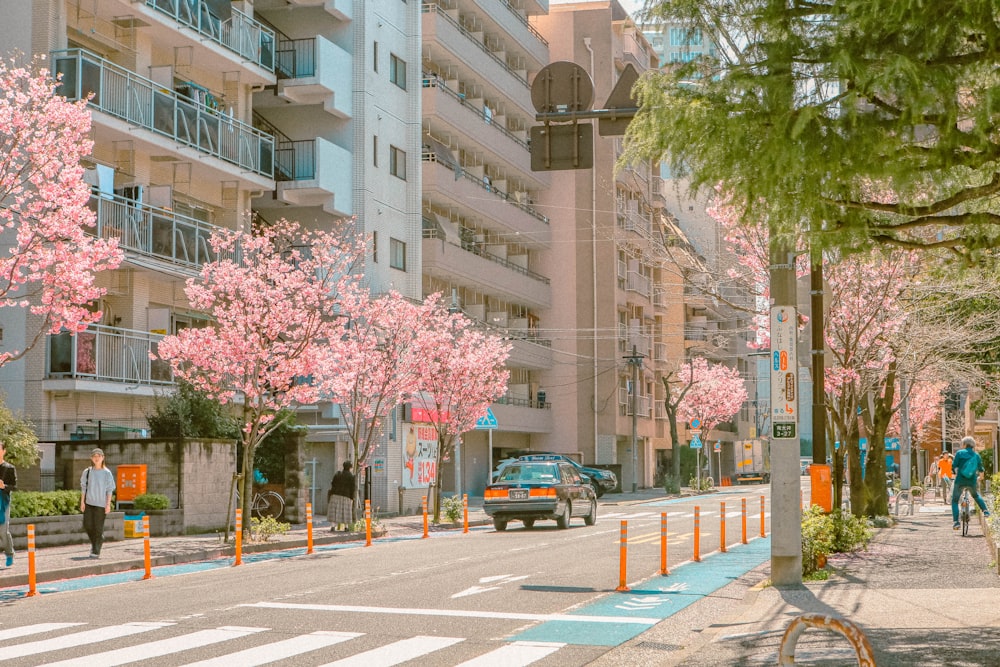 a couple of people walking down a street next to tall buildings