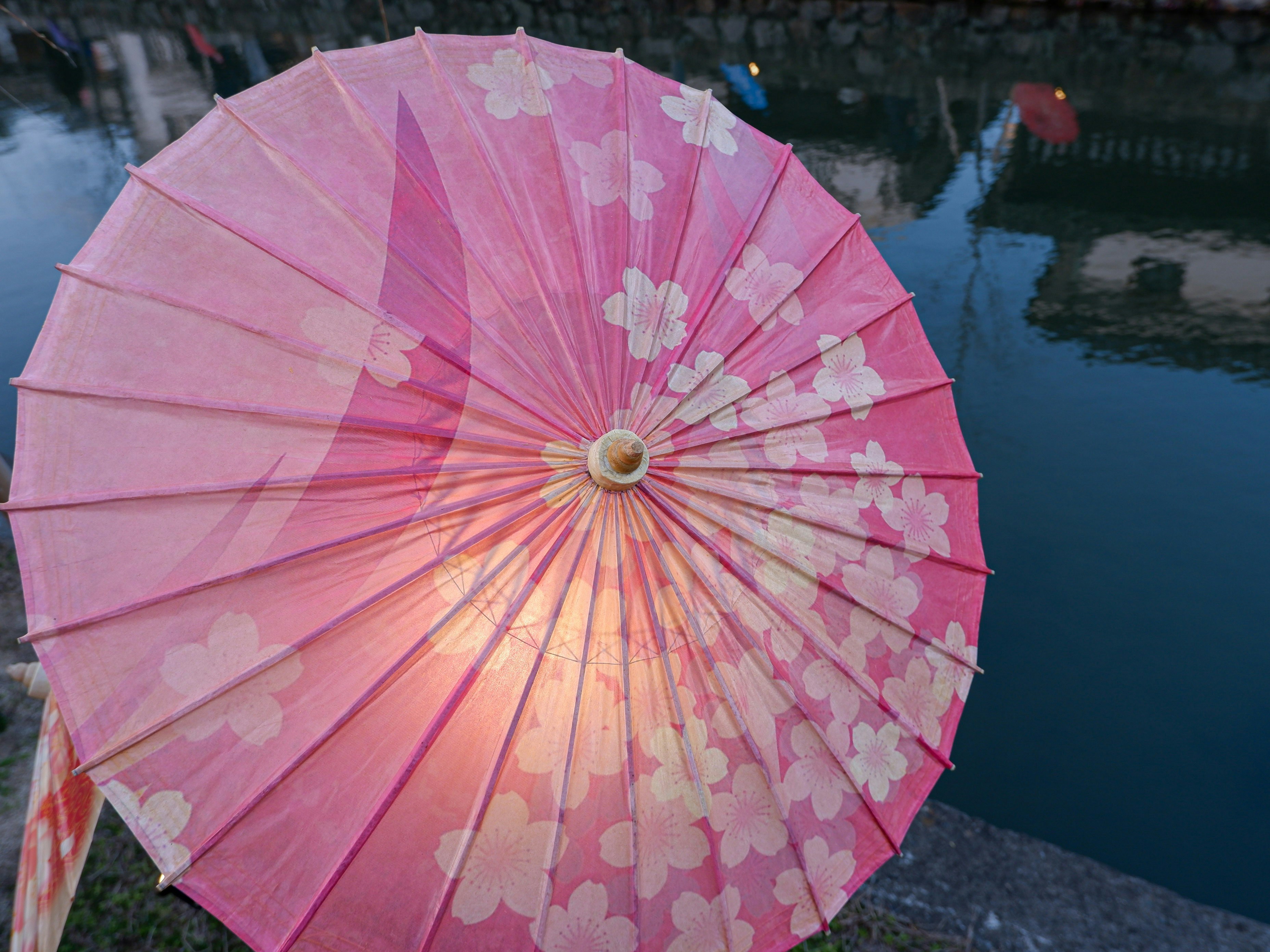 a pink umbrella with white hearts on it, Japanese umbrellas alongside the river in Kurashiki
