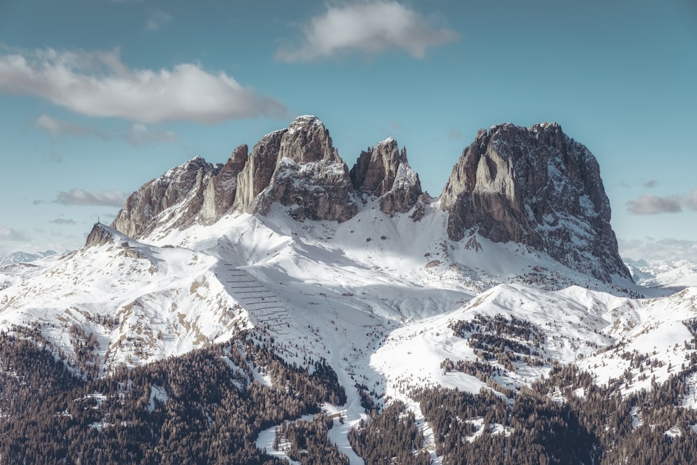 a snow covered mountain range with a few clouds in the sky