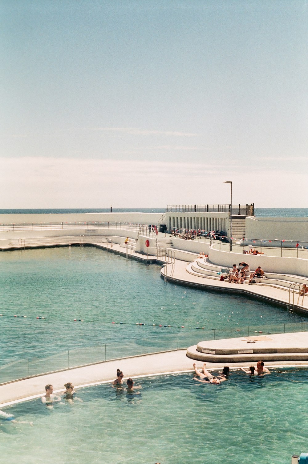 a group of people swimming in a pool next to the ocean