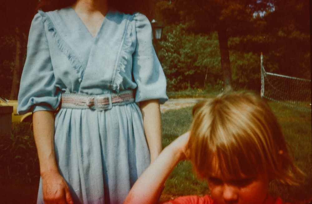 a woman in a blue dress standing next to a little girl