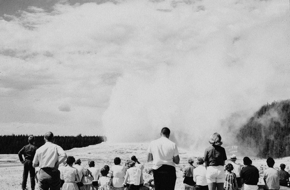 a group of people standing in front of a geyser
