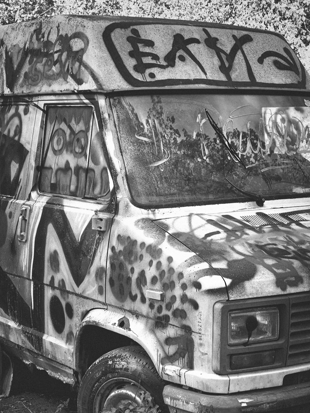 a van covered in graffiti sitting on the side of a road