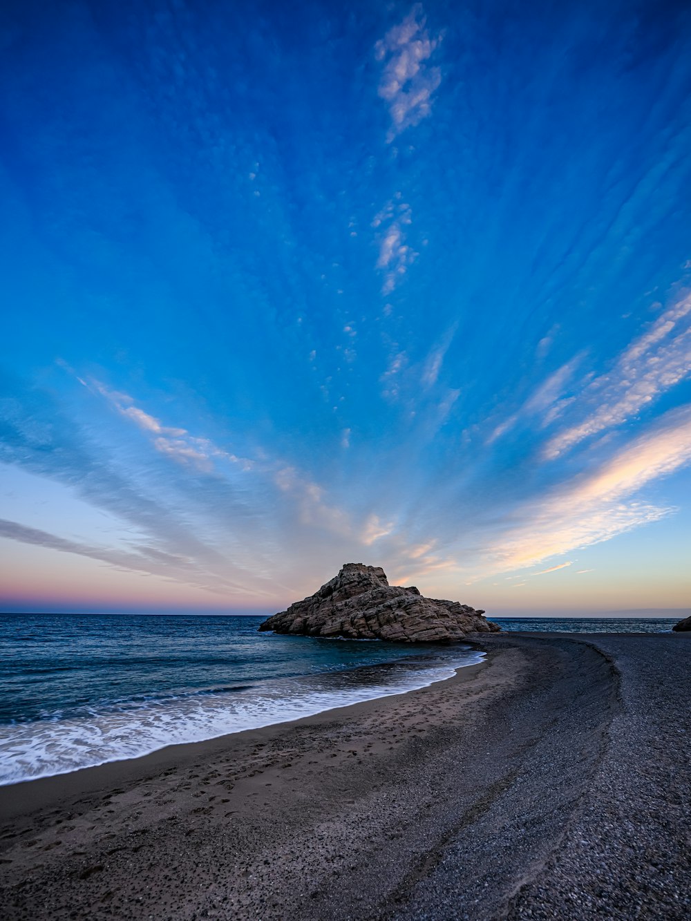 a beach with a small rock in the middle of it