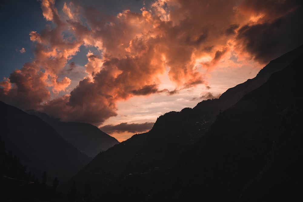 a sunset view of a mountain range with clouds in the sky