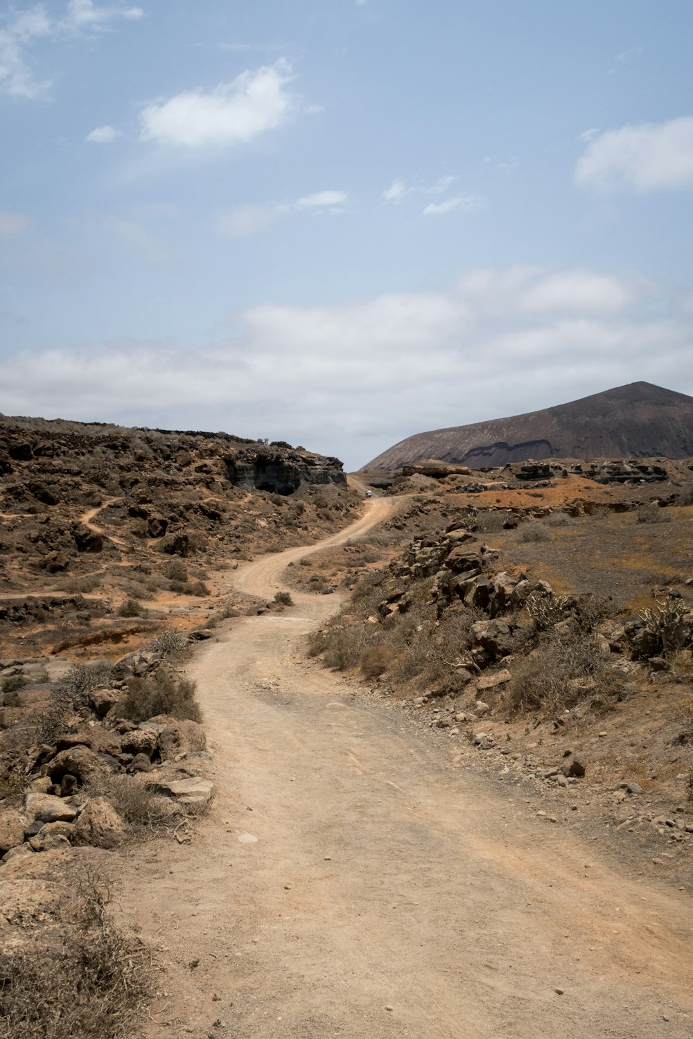 a dirt road with a hill in the background