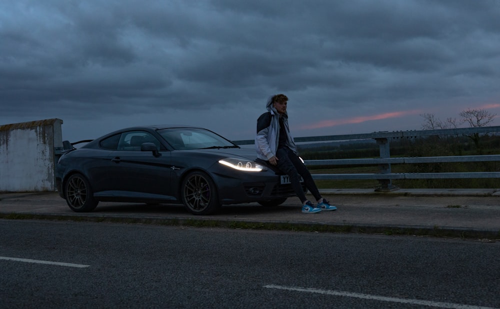 a man standing next to a car on the side of the road