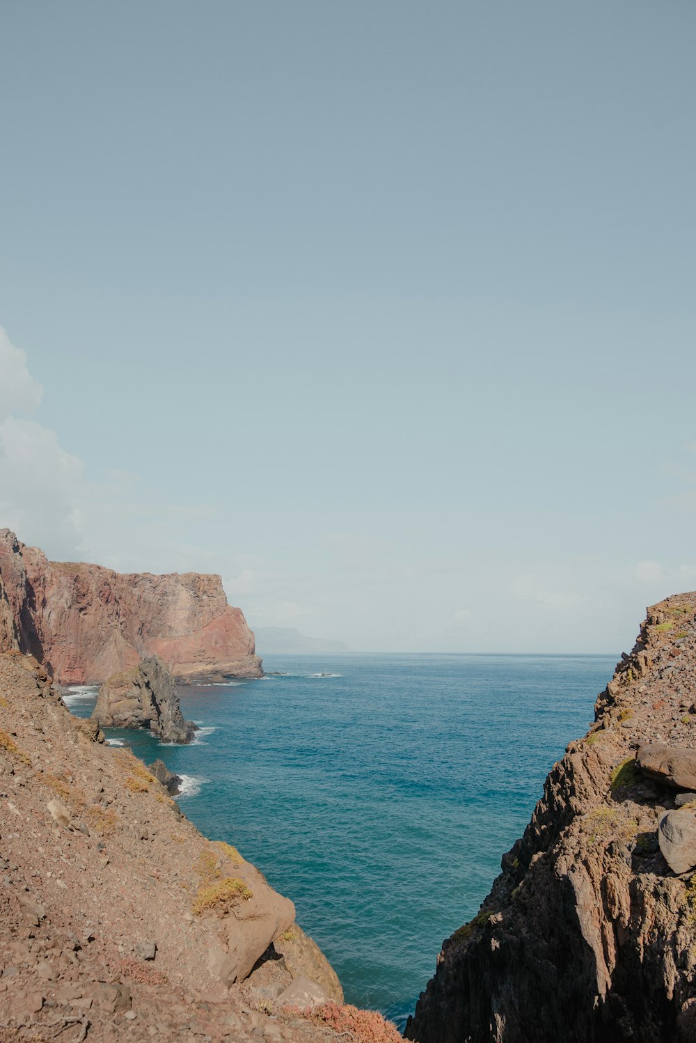 a man standing on top of a cliff next to the ocean