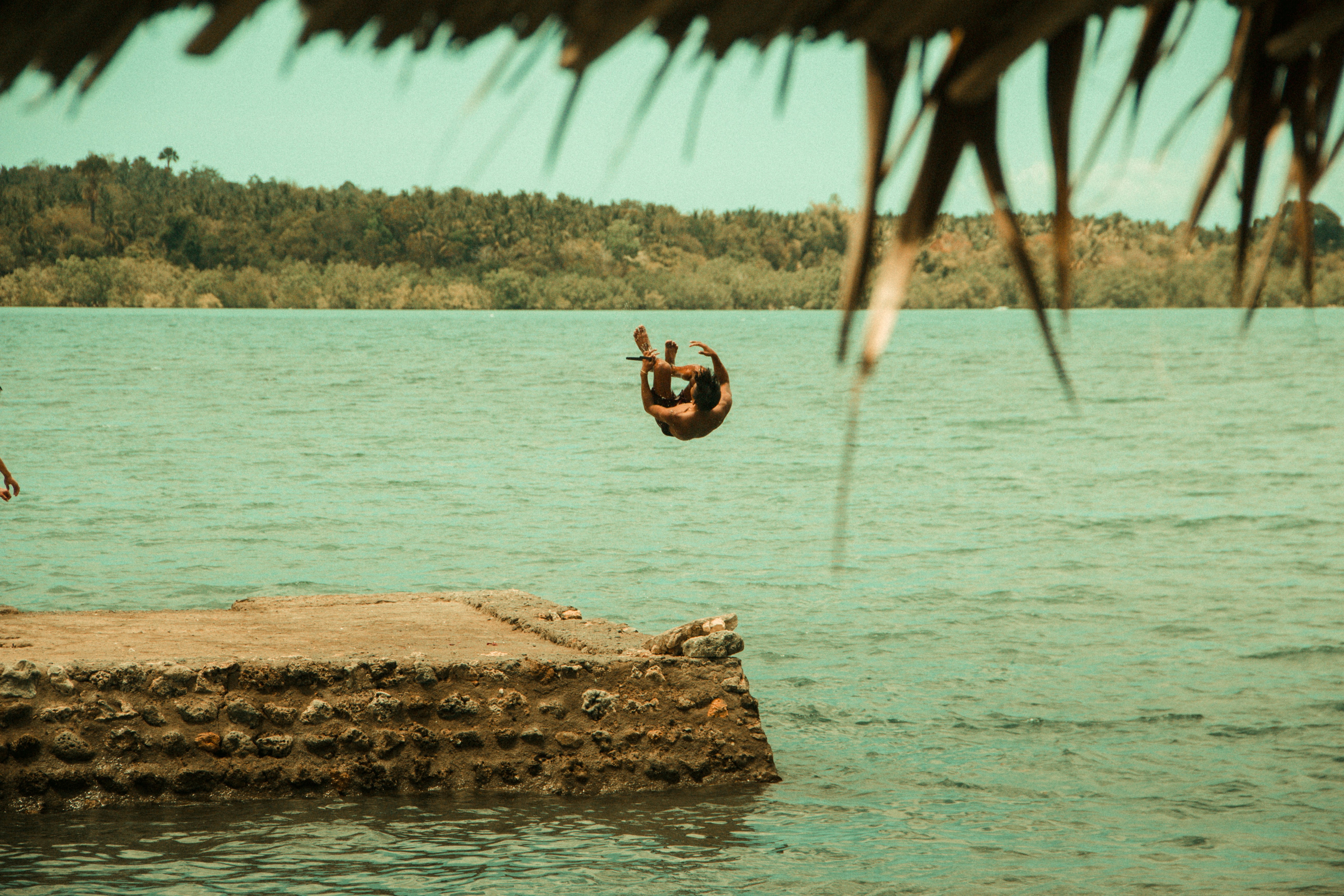 A person jumping off a rock into a body of water