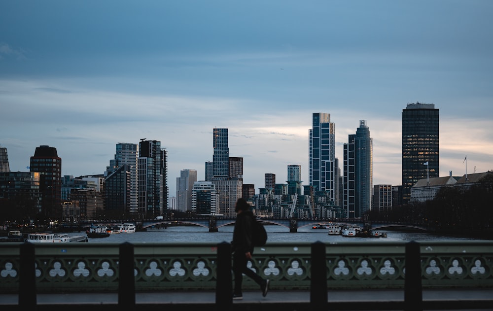 a person standing on a bridge with a city in the background