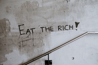 graffiti on a wall that says eat the rich