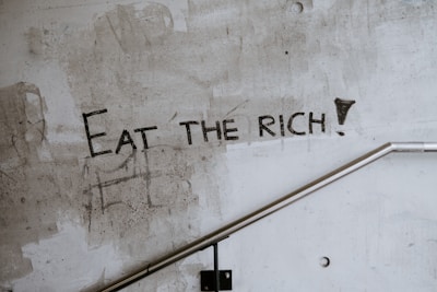 graffiti on a wall that says eat the rich