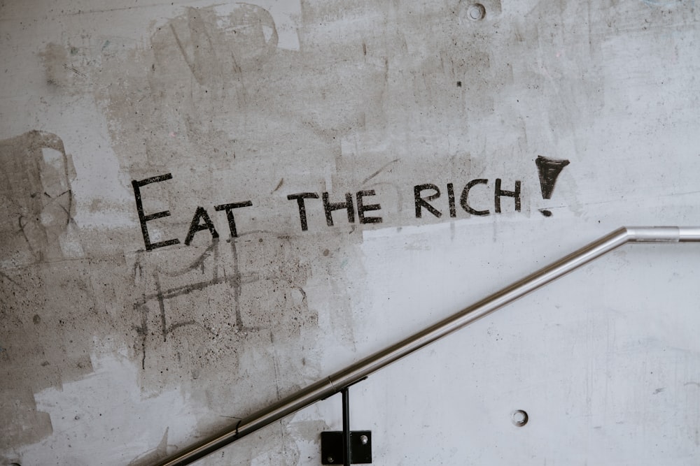 graffiti su un muro che dice mangia i ricchi