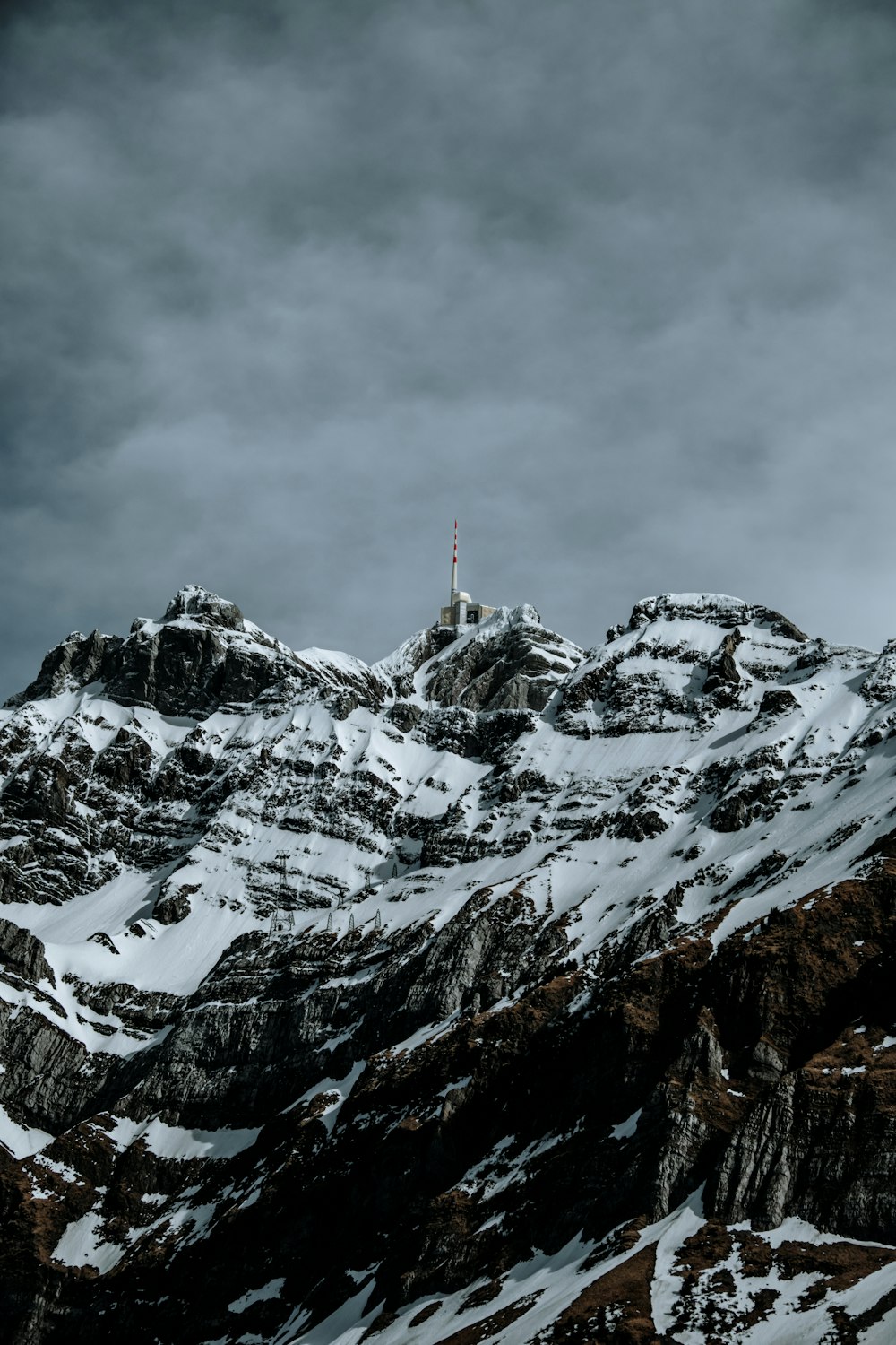 a very tall mountain covered in snow under a cloudy sky