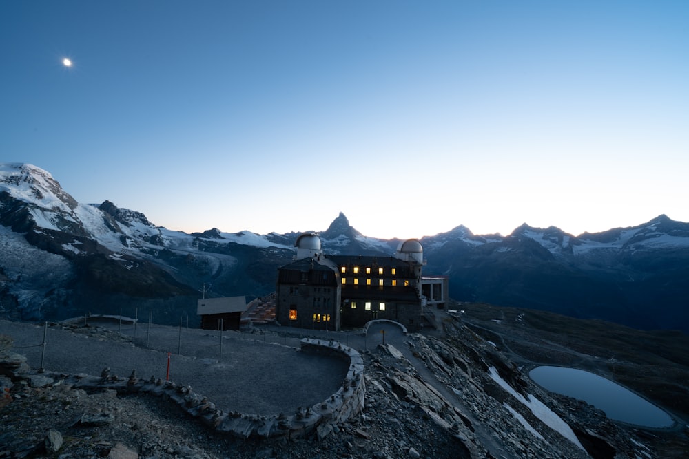 a building on top of a mountain with a moon in the sky