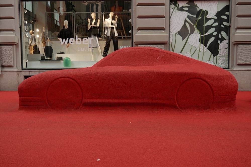 a red car on a red carpet in front of a store