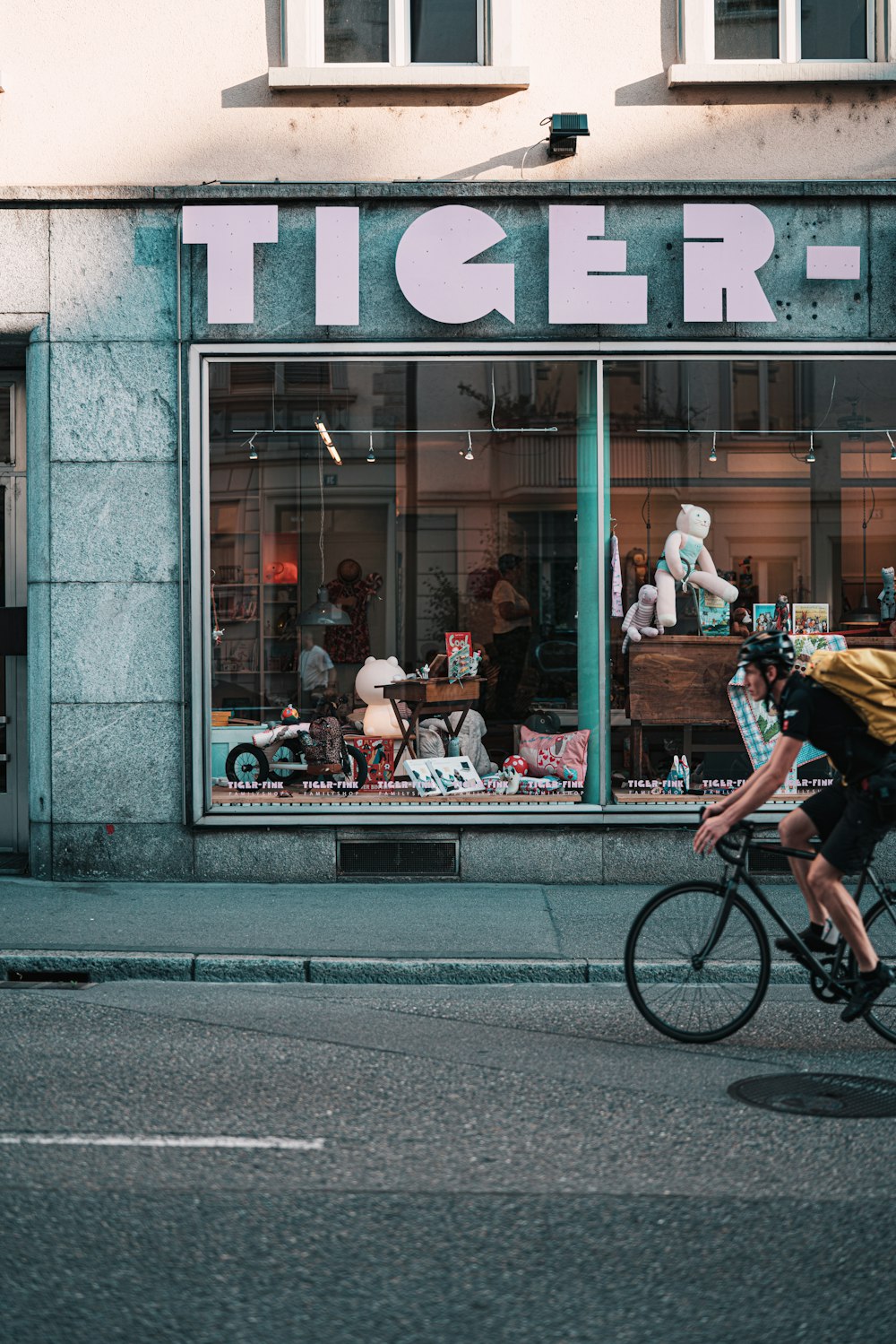 a man riding a bike down a street past a store