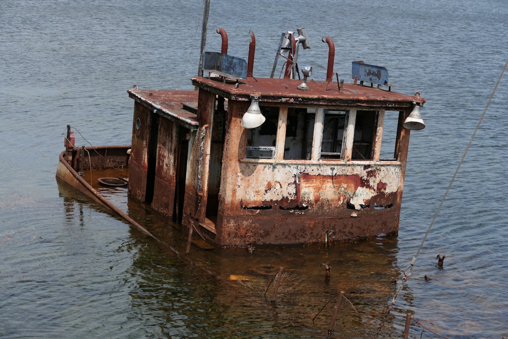 a rusted out boat floating on top of a body of water