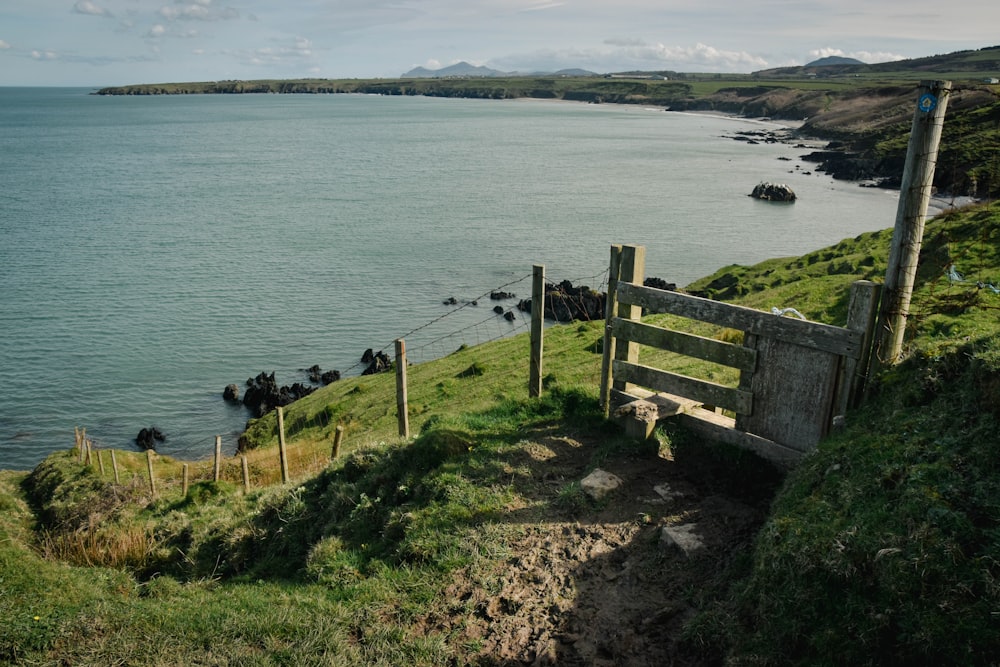 a wooden gate on the side of a hill overlooking a body of water