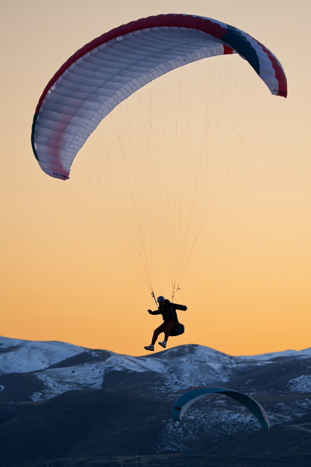 a person is parasailing in the mountains at sunset