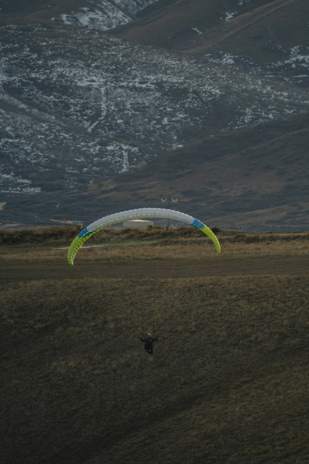 a person parasailing in a field with mountains in the background
