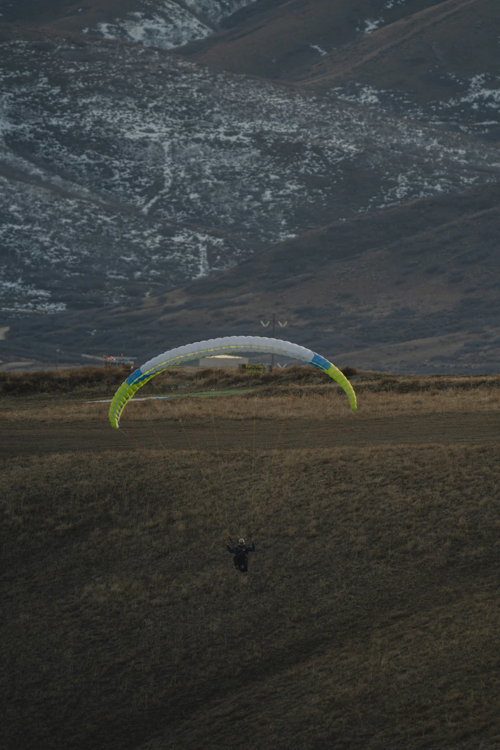 Paraglider lifting off from a grassy mountain field at sunset