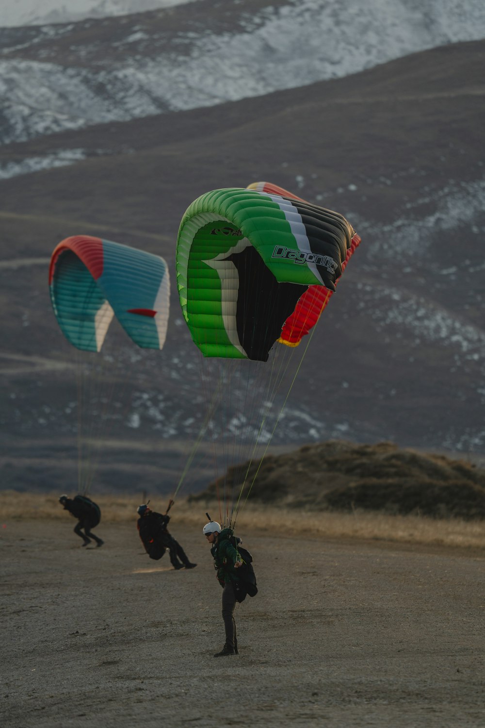 a group of people flying kites on top of a sandy beach