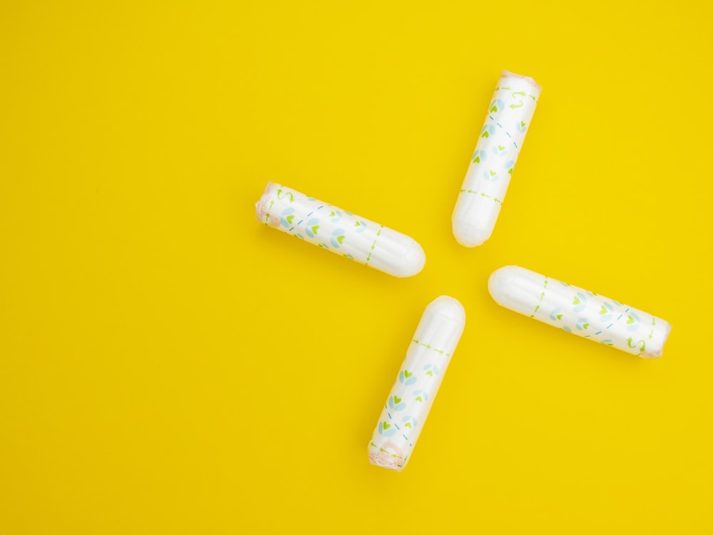 a group of four pills sitting on top of a yellow surface