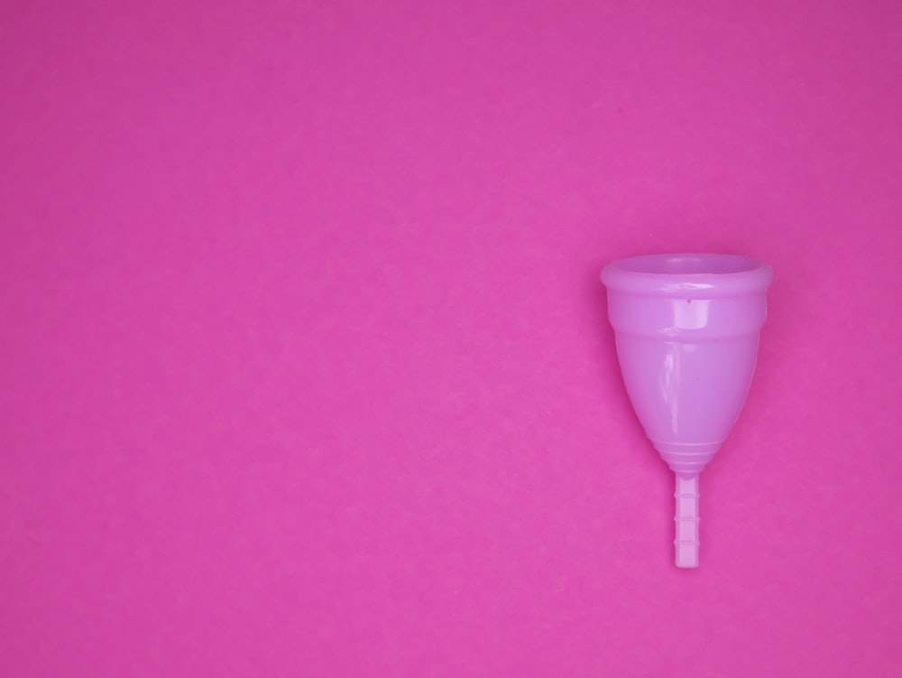 un bicchiere di plastica rosa seduto sopra una superficie rosa