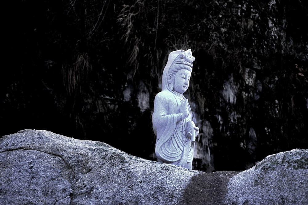 a buddha statue sitting on top of a large rock