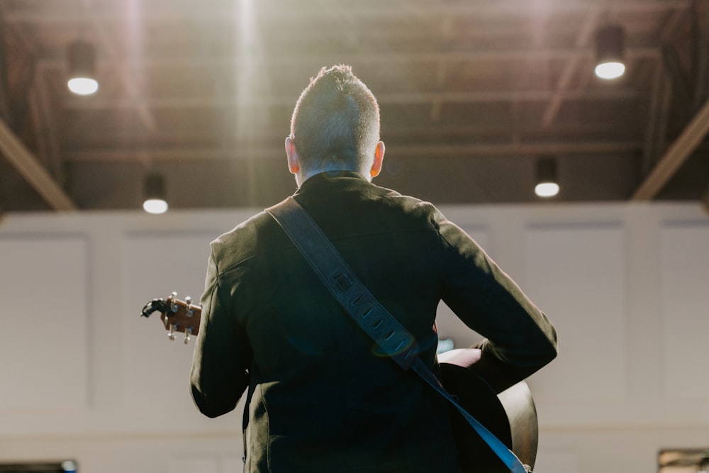 un homme avec une guitare debout dans une pièce