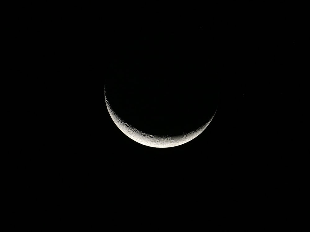 Une demi-lune est vue dans le ciel sombre