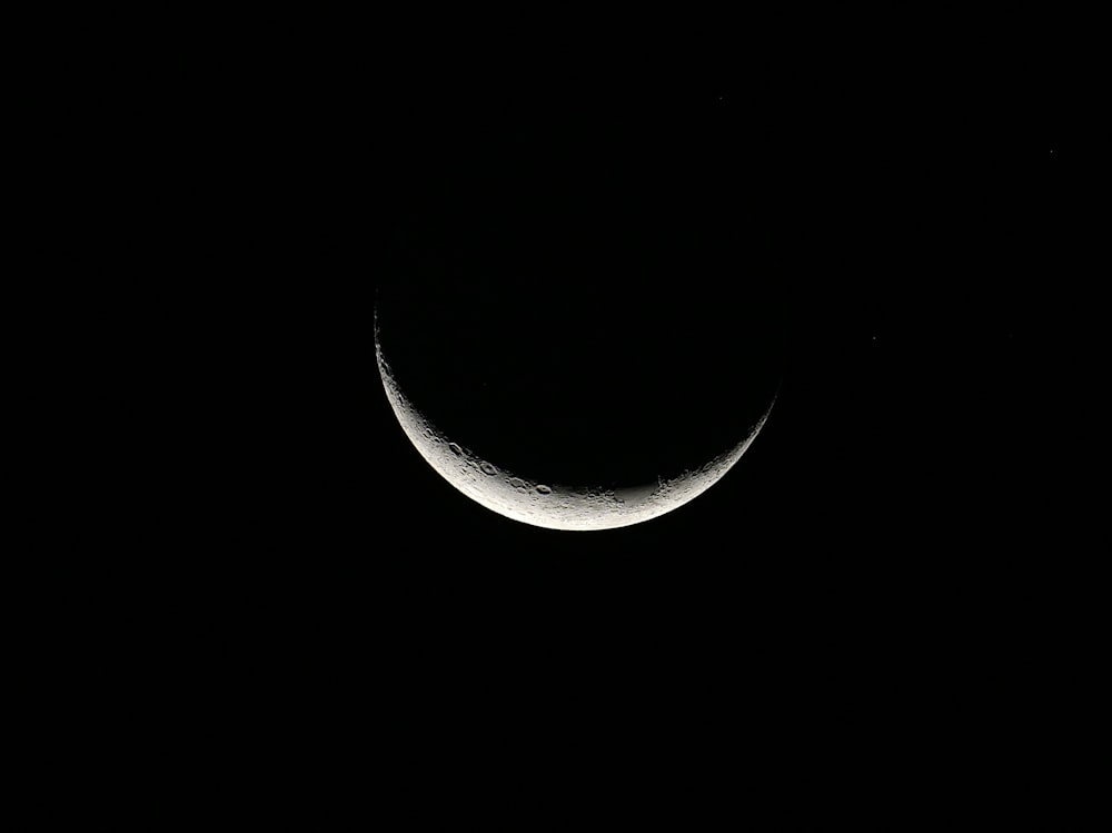 a half moon is seen in the dark sky