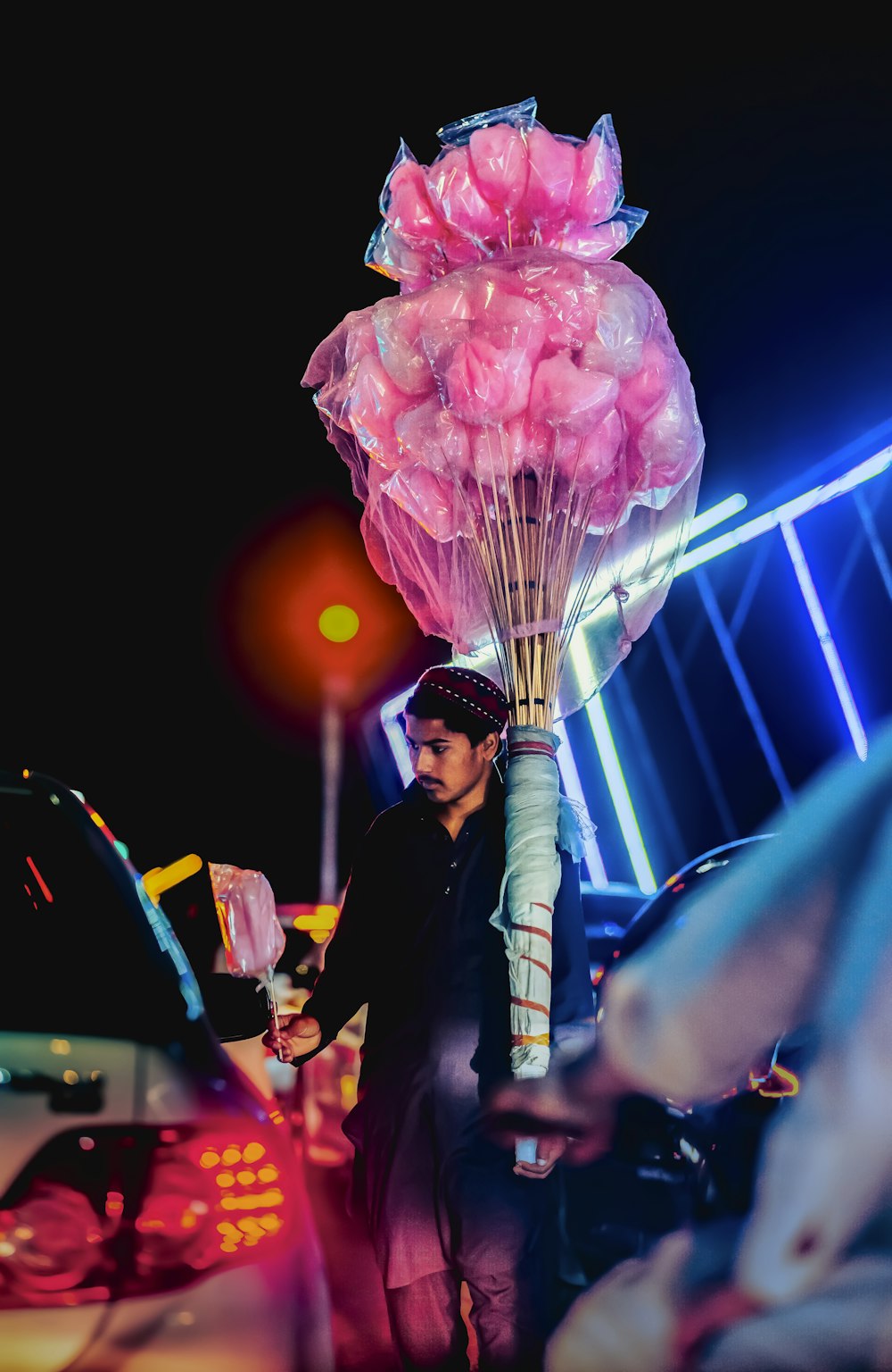 a man standing next to a car holding a bunch of balloons