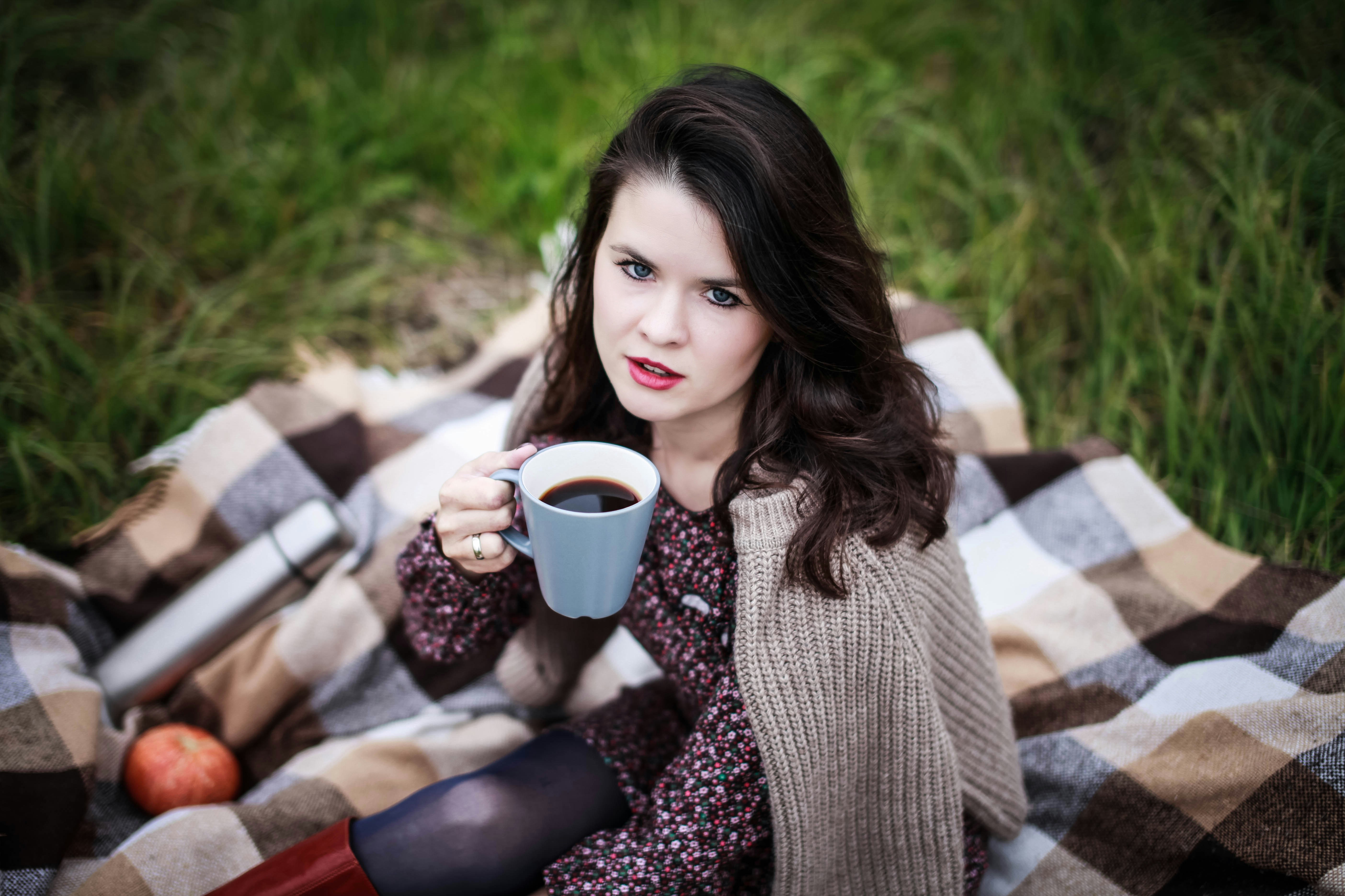 Woman holding a mug of coffee on a blanket