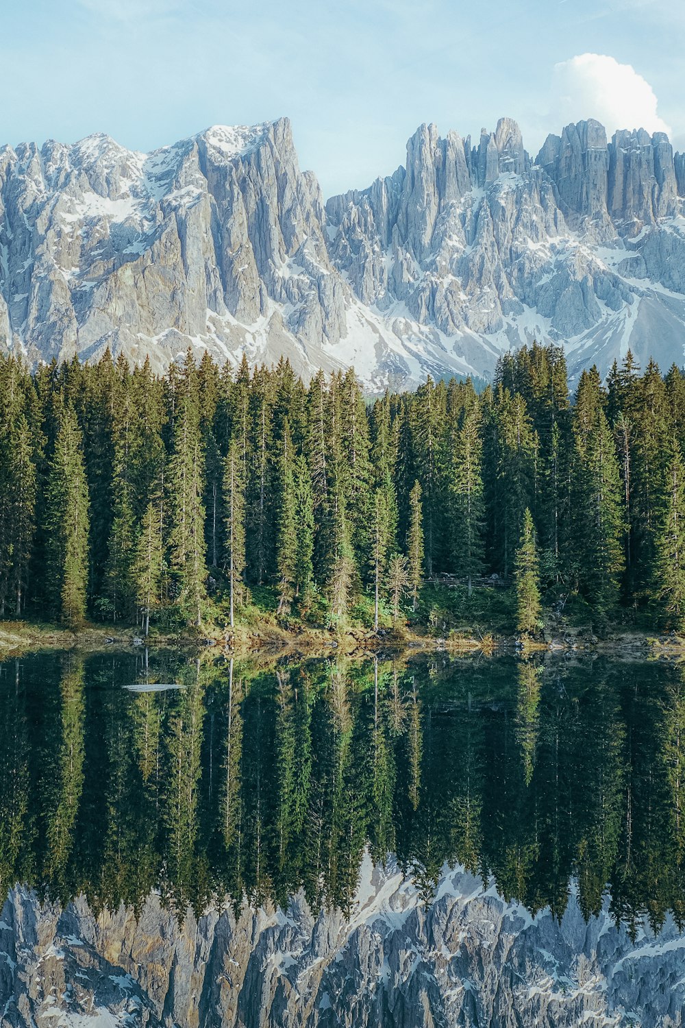 a mountain range is reflected in the still water of a lake