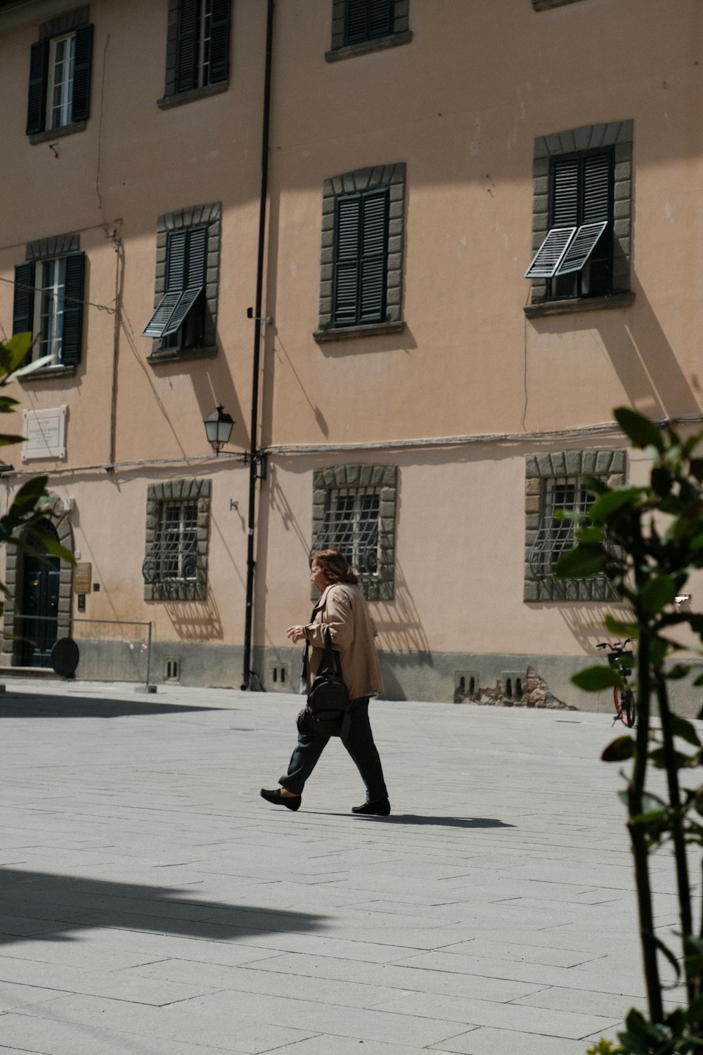 a man walking down a street past a tall building