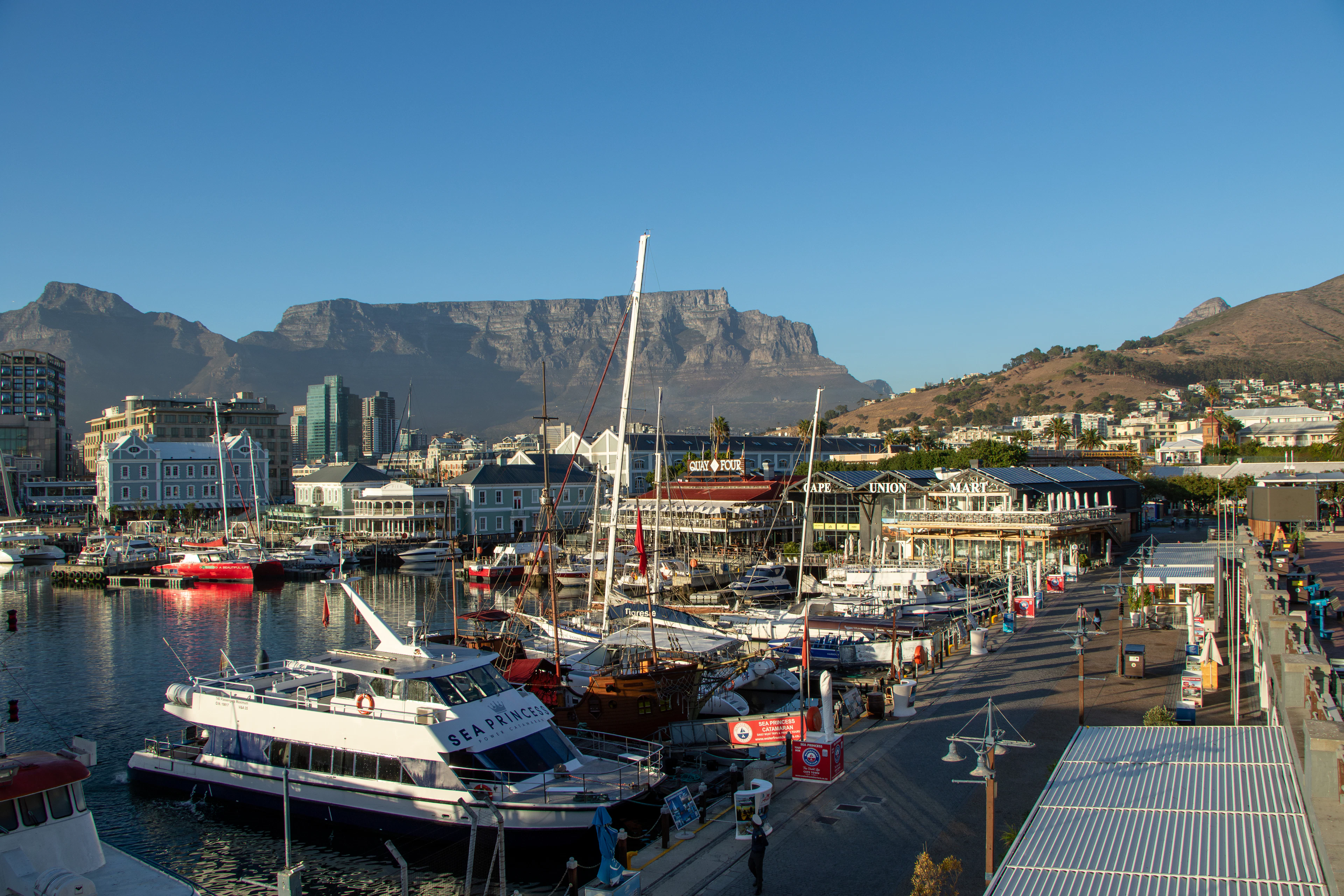 Golden-hour view over Cape Town's V&A Waterfront marina with Table Mountain rising behind the harbor.