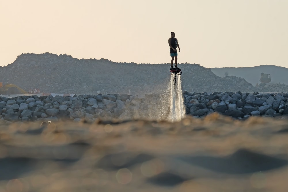 a man standing on top of a jet ski while flying through the air