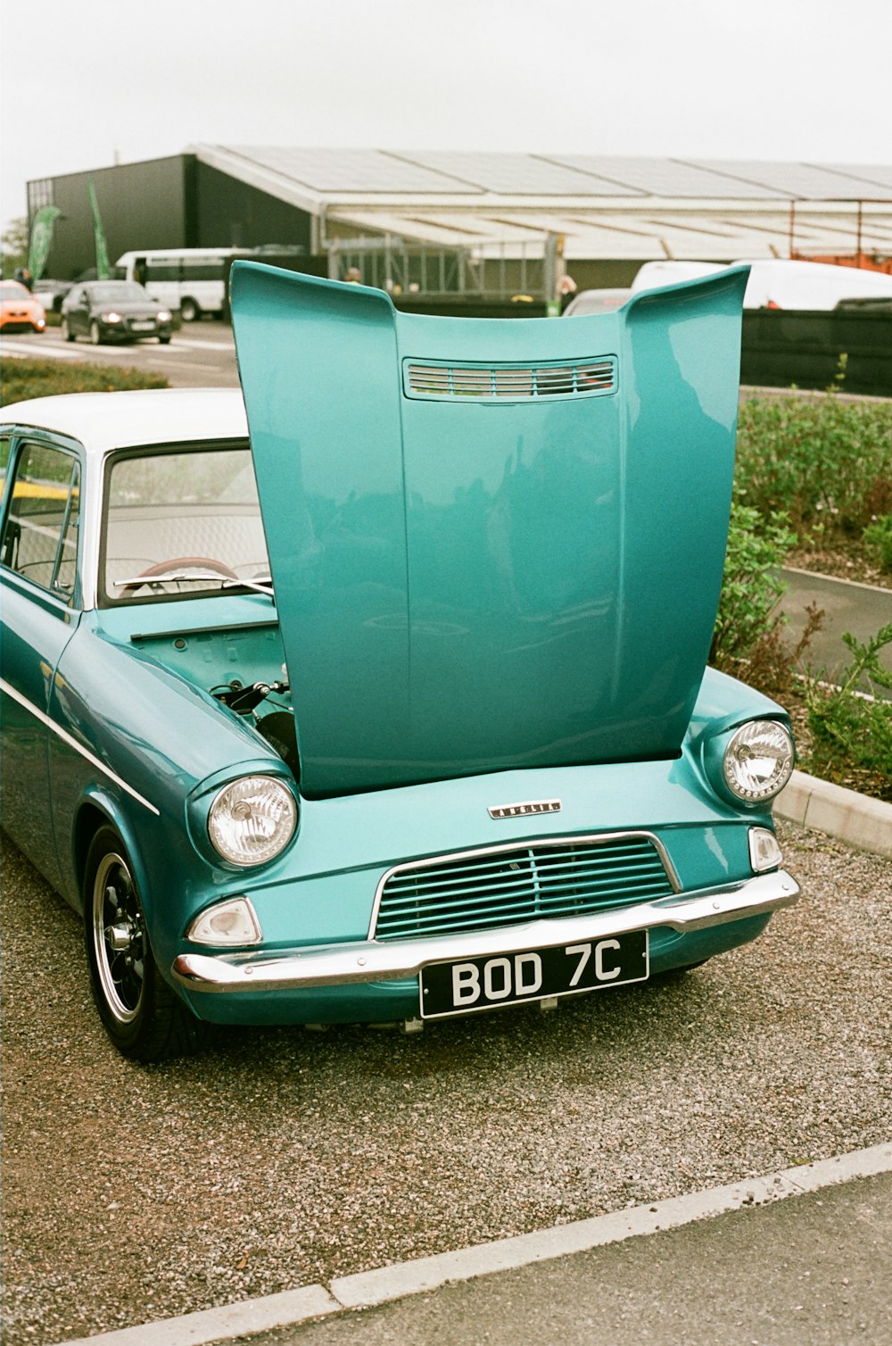 um carro azul com o capô aberto em um estacionamento