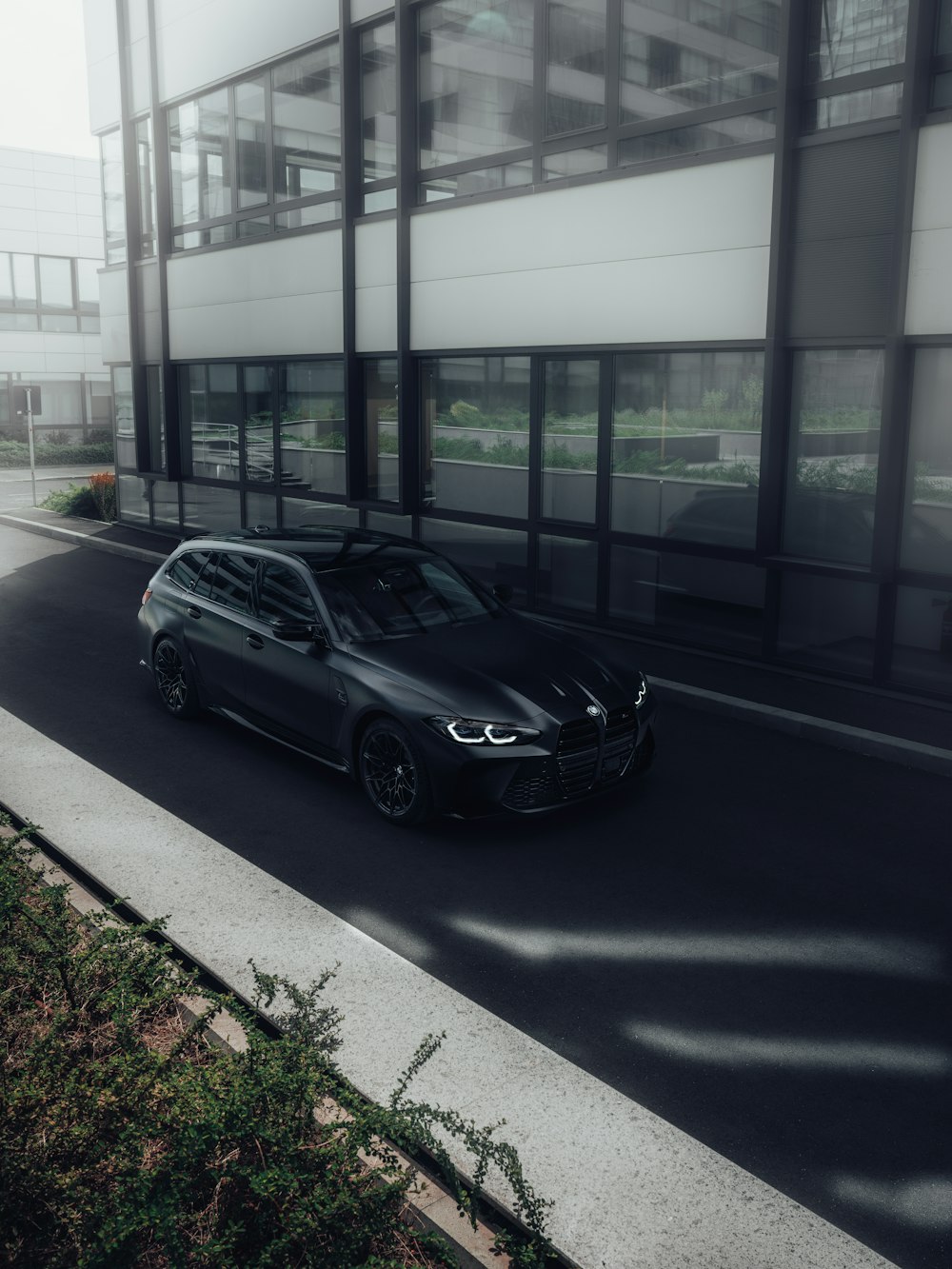 a black car driving down a street next to a tall building