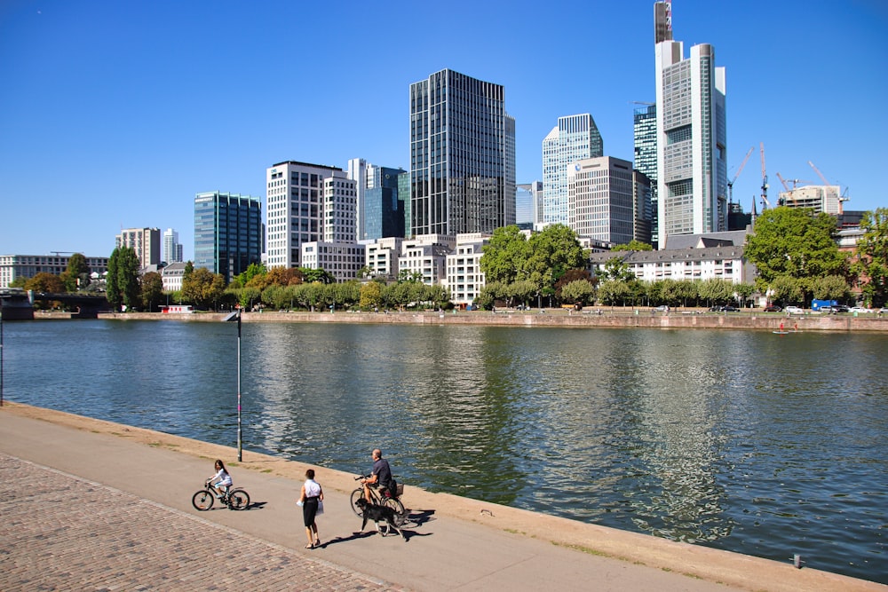 a group of people walking down a sidewalk next to a river