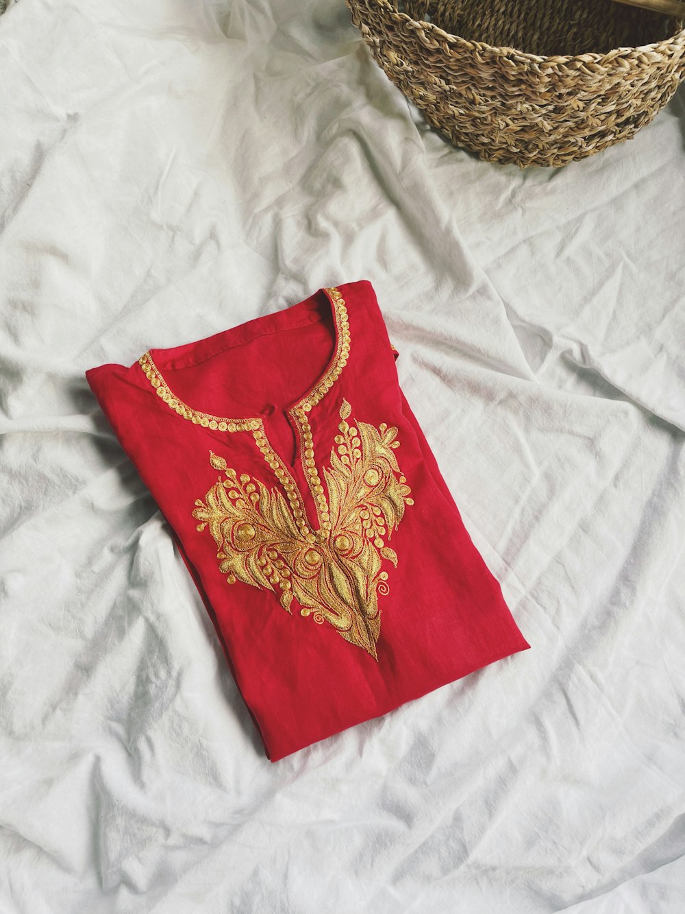 a red t - shirt with a gold embroidered design on it