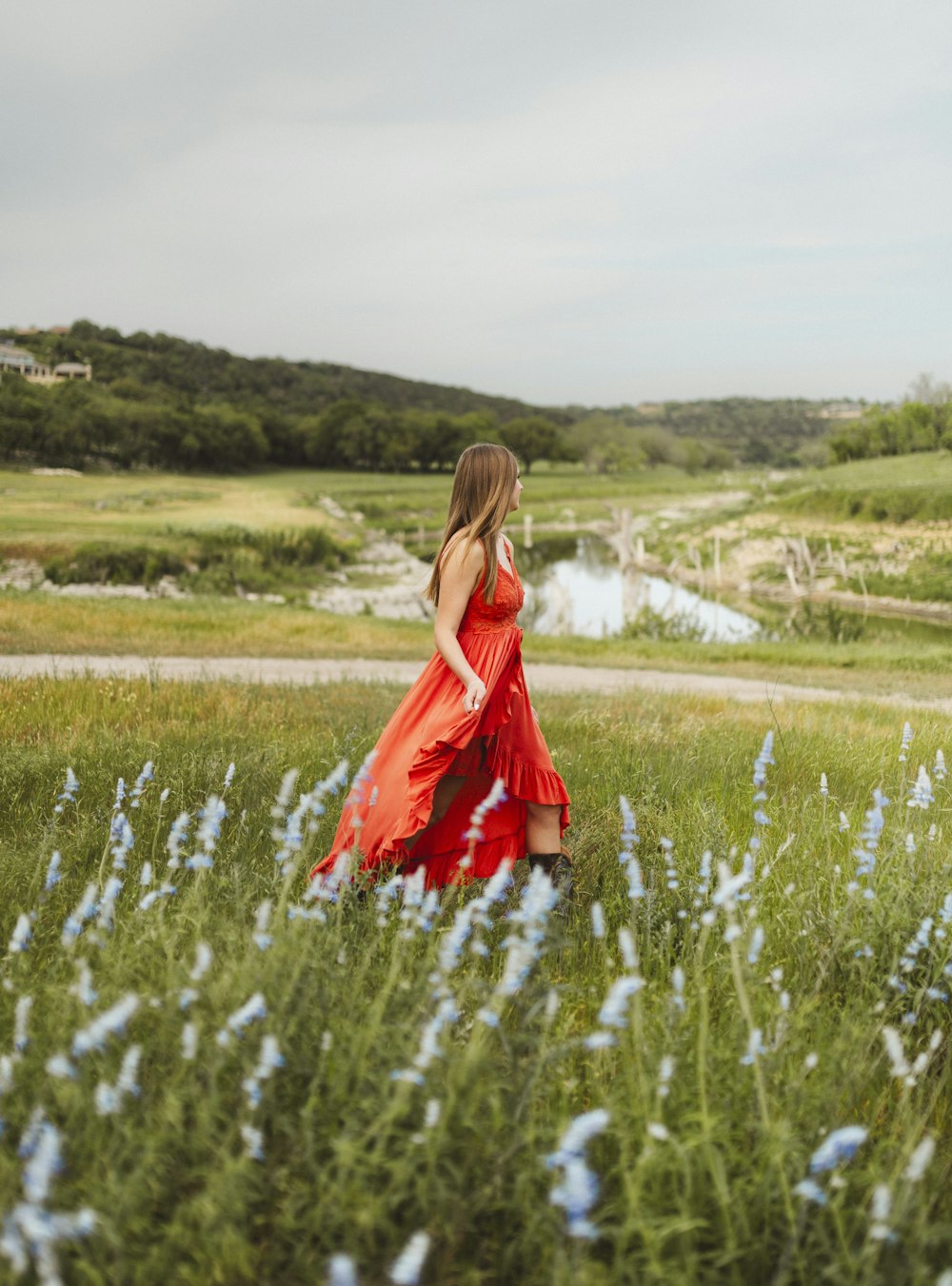 a woman in a red dress walking through a field
