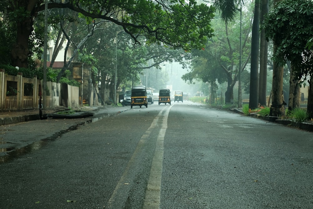 a couple of trucks driving down a street next to trees